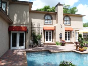 Red awnings over windows and doors in a backyard